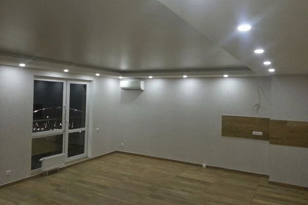 Просторная комната с белыми обоями и многоуровневым потлком